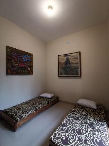 two twin beds in a room with two pictures on the wall at Mawartiga Homestay in Demangan