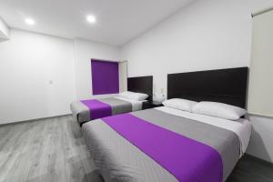 two beds in a room with purple and white at La Terraza Hotel in Jalpan +23 photos