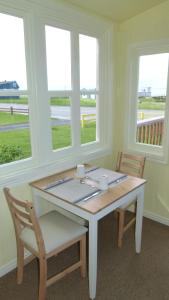 a table and two chairs in a room with windows at La Maison entre Mer Montagnes in Cap-Chat