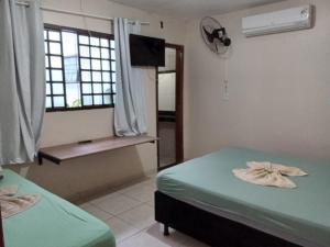 リオ・ベルデにあるHotel Por Do Solのベッド2台、テレビ、窓が備わる客室です。 +5枚の写真