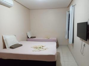 リオ・ベルデにあるHotel Por Do Solのテレビ付きの小さな白い部屋にベッドが2つある