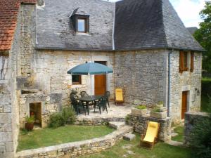 ein Steinhaus mit einem Tisch und einem Sonnenschirm in der Unterkunft Gîte Borrèze, 4 pièces, 6 personnes - FR-1-616-152 in Borrèze