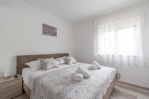 a white bedroom with a bed with towels on it at Villa Strikina kuca in Slivno +41 photos