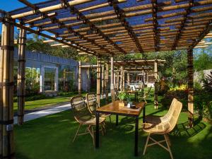 a patio with a table and chairs under a pergola at The Tempekan Heritage in Uluwatu