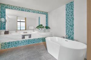 a bathroom with a tub and a large mirror at Holiday Inn Resort Ho Tram Beach by IHG in Ho Tram