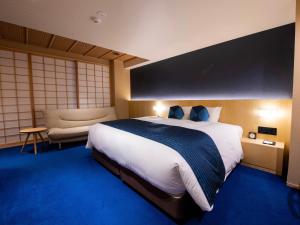 um quarto de hotel com uma cama grande e uma cadeira em Homm Stay Nagi Shijo Kyoto By Banyan Group em Quioto