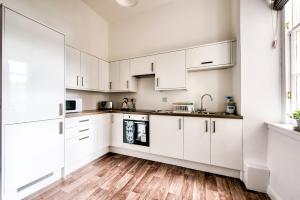 una cucina con armadietti bianchi e pavimenti in legno massello di Lothian Road - perfect city centre location. a Edimburgo