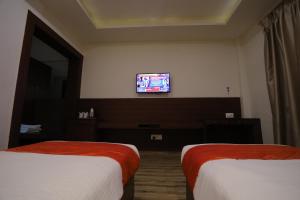 um quarto de hotel com duas camas e uma televisão na parede em Hotel Marygold em Agra