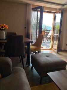 ein Wohnzimmer mit einem Tisch und Stühlen sowie einem Balkon in der Unterkunft Casa Nostra Kop in Kopaonik