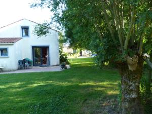 a tree in the yard of a white house at Chez Marcel Gite PMR in La Marne