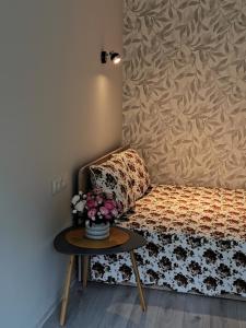 a room with a bed and a table with flowers on it at Upės apartamentai in Biržai