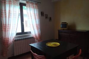 Zimmer mit einem Tisch, einem TV und einem Fenster in der Unterkunft Appartamento nel verde tra Cinque Terre e Versilia in Barbarasco