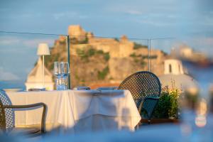 a table with a white table cloth and chairs with a glass at Hotel Villa Durrueli Resort & Spa in Ischia