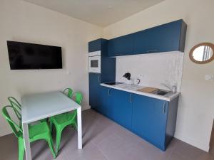 een keuken met blauwe kasten, een tafel en een wastafel bij Appartement Escapade Vitaminée - Maison d'Aligre in Marans