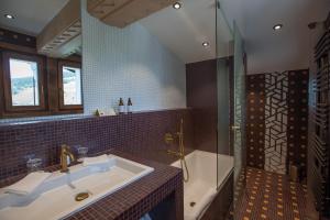 a bathroom with a tub, sink, and shower at Au Coin Du Feu in Megève