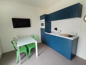 een keuken met blauwe kasten en een witte tafel en stoel bij Appartement Escapade Vitaminée - Maison d'Aligre in Marans