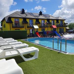 a swimming pool with lounge chairs and a building at Rezydencja Kwiatano - Basen & Jacuzzi & Sauna & Plac Zabaw in Grzybowo