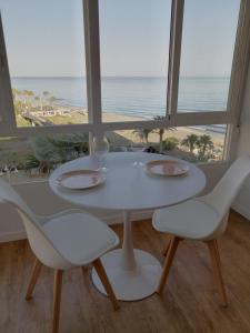- une table et des chaises blanches avec vue sur la plage dans l'établissement HH Apartamento Algarrobo costa, à Algarrobo-Costa