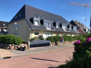 a person walking down a sidewalk in front of a house at direktamstrand-sylt in Westerland (Sylt)