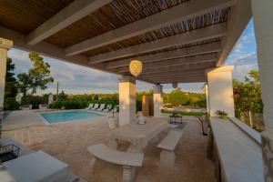 Un patio con mesa y sillas y una piscina. en Casale del Gelso, en Monopoli