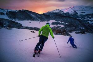 two people are skiing down a snow covered mountain at Casa Cris in Brentonico