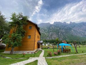 una casa in legno con tavolo e ombrellone blu di Guesthouse Mehmeti a Valbona Altre 27 foto