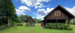 a wooden house with a gazebo in a yard at Merkiokrantas Trobelė ant upės kranto in Puvočiai