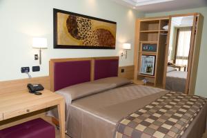 a bedroom with a bed and a desk with a phone at Artemis Hotel in Cefalù