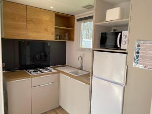 małą kuchnię z lodówką i kuchenką mikrofalową w obiekcie Mobilhome tout confort R10 domaine de lanniron w mieście Quimper