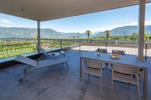 d'une terrasse avec une table, des chaises et des montagnes. dans l'établissement Paulsner Feldhof, à Appiano sulla Strada del Vino