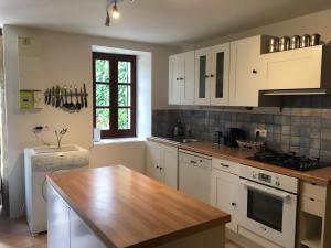 cocina con armarios blancos y encimera de madera en L'Olivier en Puisseguin