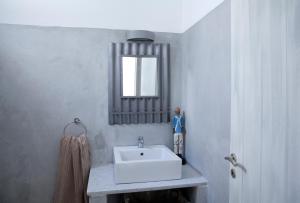 een badkamer met een witte wastafel en een spiegel bij Alfa Luxury Villas in Chrissi Akti