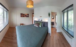 a bedroom with a blue bed and two windows at Ten Hove Brugge in Bruges