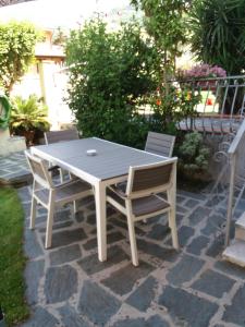 une table et des chaises blanches sur une terrasse en briques dans l'établissement Casa Enrica, à Montignoso