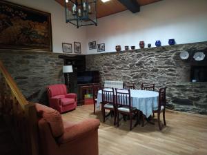 ein Esszimmer mit einem Tisch, Stühlen und einer Steinmauer in der Unterkunft Casa O Castelo en Touro in Touro