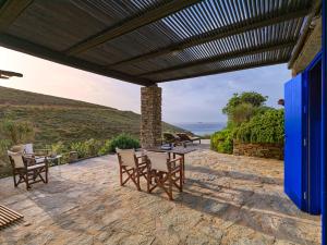 a patio with a wooden pergola and tables and chairs at Agelos Beachfront Villa in Korissia