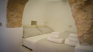 - une chambre avec un lit doté de draps blancs et de serviettes dans l'établissement Trulli Brunone, à Castellana Grotte