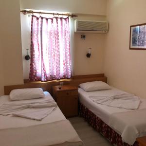 two beds in a room with a window with pink curtains at Üstün Apart in Marmaris