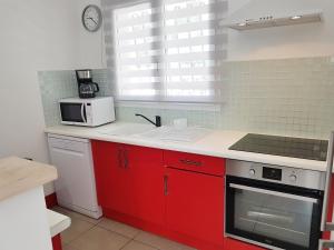 a kitchen with red cabinets and a microwave at SANTA LUCIA in Sainte-Lucie de Porto-Vecchio
