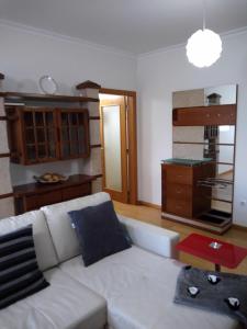 ein Wohnzimmer mit einem weißen Sofa und einer Küche in der Unterkunft Alto Aguieira in Viseu