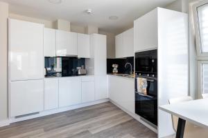 a kitchen with white cabinets and black appliances at The Westwood Summer Accommodation in Galway