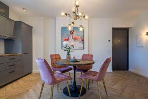 a dining room with a table and pink chairs at Smėlynas Boutique & SPA in Palanga