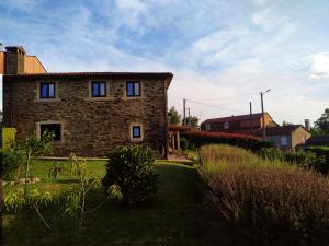 ein Steinhaus mit blauen Fenstern im Hof in der Unterkunft Casa O Castelo en Touro in Touro