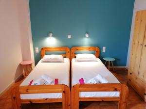 two twin beds in a room with a blue wall at Perdika Mare Guesthouse in Perdika