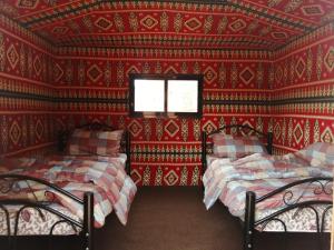 two beds in a room with red wallpaper at Bedouins life camp in Aqaba