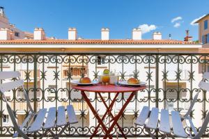 einen Tisch auf einem Balkon mit 2 Stühlen und Getränken in der Unterkunft La Colline YourHostHelper in Cannes