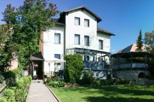 una grande casa bianca con un vialetto di mattoni nel cortile di Pension Am Kirschberg a Weimar