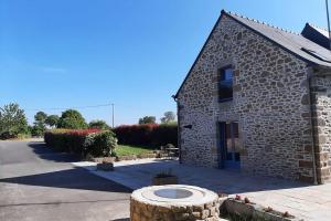 a stone building with a tree stump in front of it at LA MAISON BLEUE in Saint-Sauveur-des-Landes