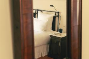 a bed with white pillows and a lamp on a table at Hotel la Ponche in Saint-Tropez