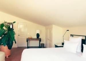 a bedroom with a white bed and a plant at Hotel la Ponche in Saint-Tropez